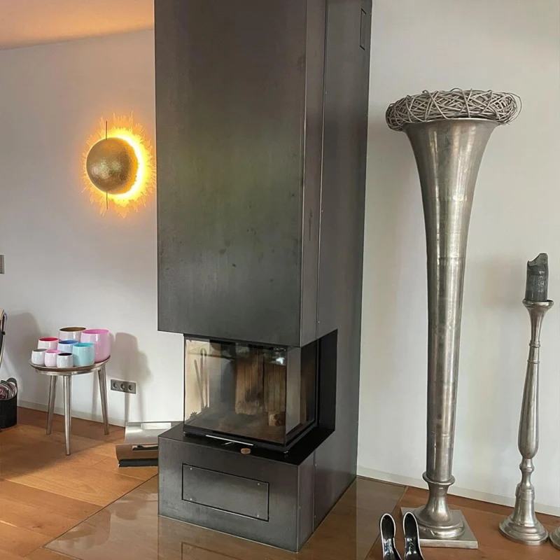 Catellani & Smith PostKrisi W 40 LED Wandleuchte Ø 40cm neben einem modernen Kamin im Wohnzimmer.