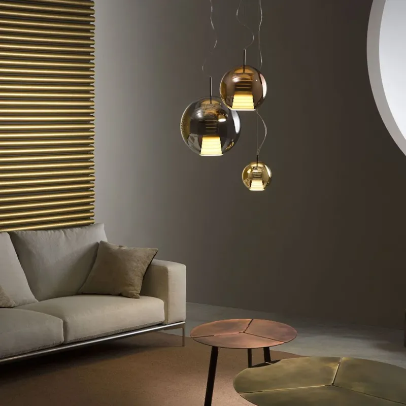 Fabbian Beluga Royal LED-Pendelleuchte Ø20cm in elegantem Wohnzimmer mit metallisierten Oberflächen und warmen Lichtreflexionen.