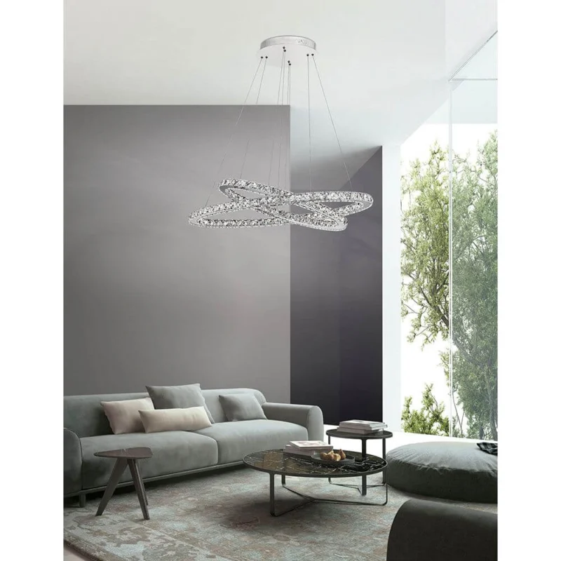 Celine LED Kristall-Hängeleuchte Glas Chrom über modernem Wohnzimmer mit Sofa und Fenster