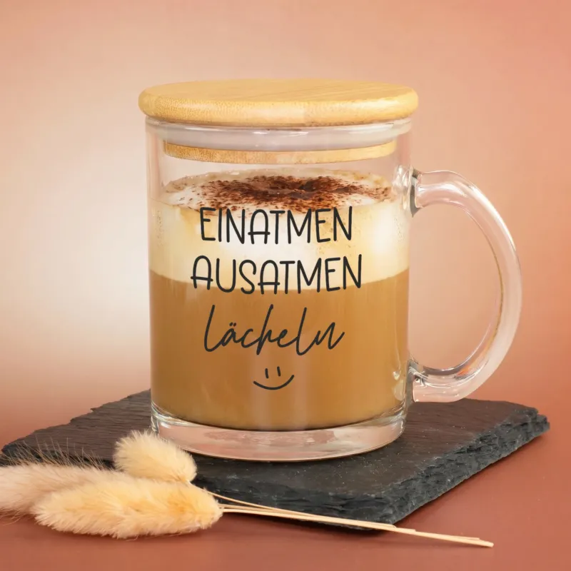 Glastasse mit Cappuccino, Bambusdeckel und Smiley-Aufdruck Einatmen Ausatmen Lächeln