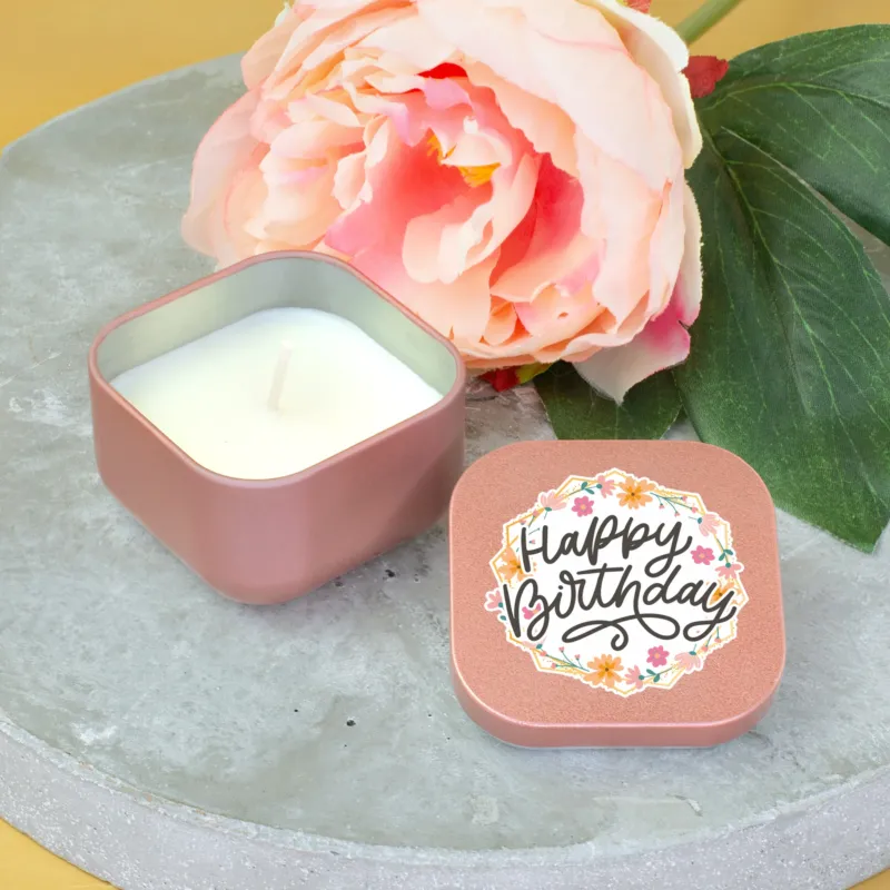 Roségoldene Mini Duftkerze mit Happy Birthday Deckel neben großer Blume dekoriert
