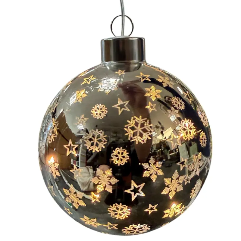 Eine glänzende silberne LED-Dekokugel ist mit Schneeflocken- und Sternmotiven versehen und reflektiert ihre Umgebung.