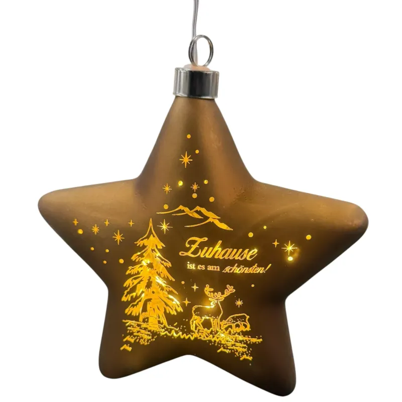 Ein sternförmiger, brauner LED-Dekoanhänger mit warmweißem Licht zeigt eine winterliche Szene mit Tannenbaum, Hirsch und dem Schriftzug „Zuhause ist es am schönsten!“.