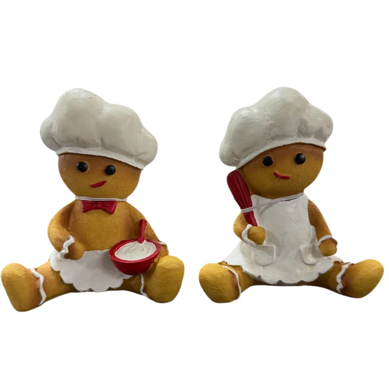 Zwei Lebkuchen-Dekofiguren in Braun mit weißen und roten Details, freigestellt vor weißem Hintergrund, jeweils sitzend mit Küchenutensilien in den Händen.
