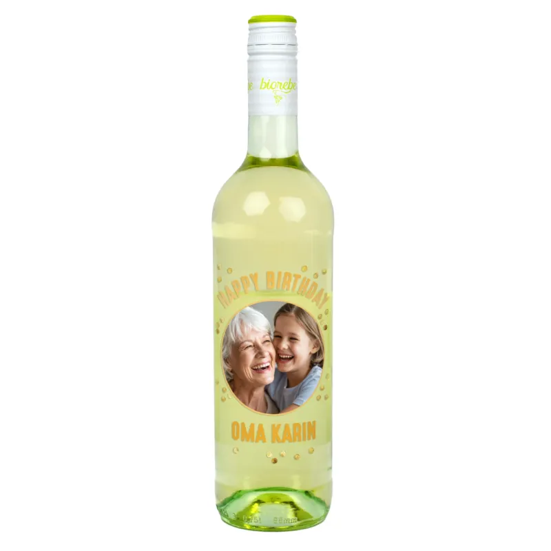 Weißweinflasche mit personalisiertem Etikett „Happy Birthday Oma Karin“ und Foto von lachender Großmutter mit Enkelin, goldene Punkte als Dekor.