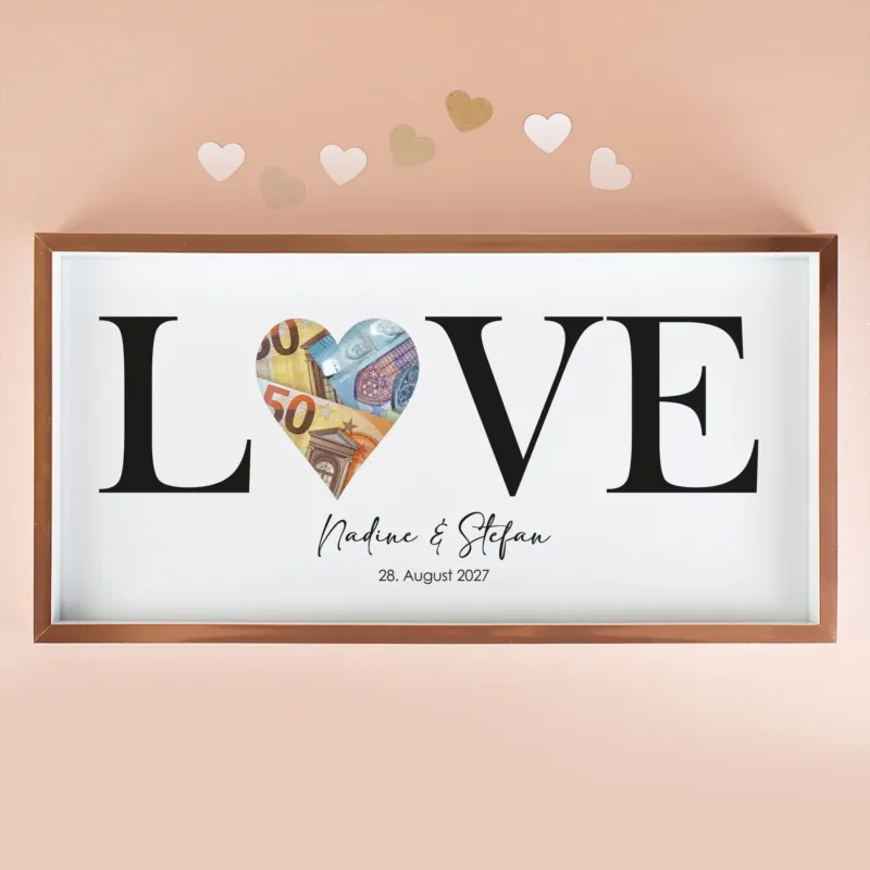Geldgeschenk Bilderrahmen mit LOVE Motiv, Namen Nadine und Stefan, Datum und Euro-Scheinen in der Herzöffnung vor rosa Hintergrund