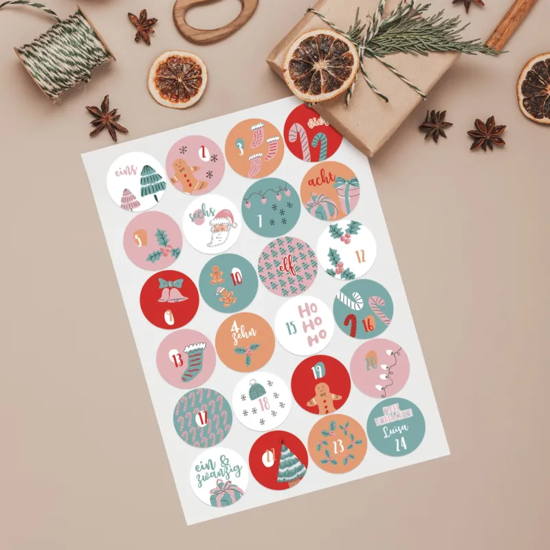 Bogen mit 24 runden Adventskalender-Aufklebern in Rosa & Türkis, nummeriert von 1 bis 24 dekoriert mit kleinen Geschenken und Zubehör