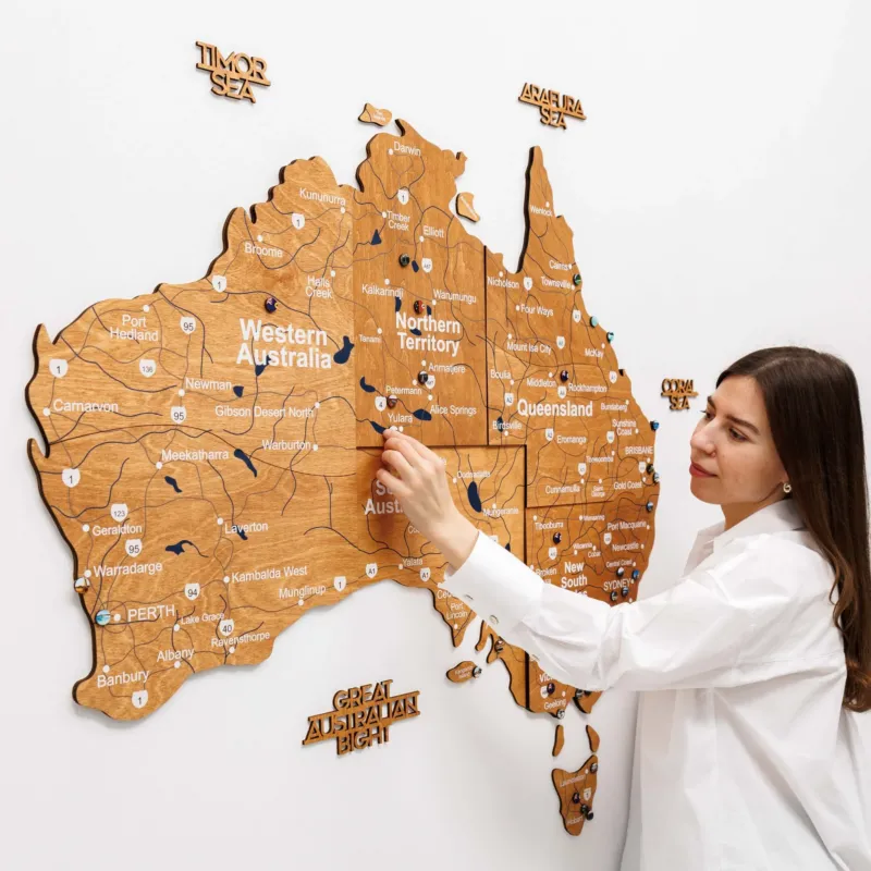 Woman interacting with a wooden map of Australia on a white background