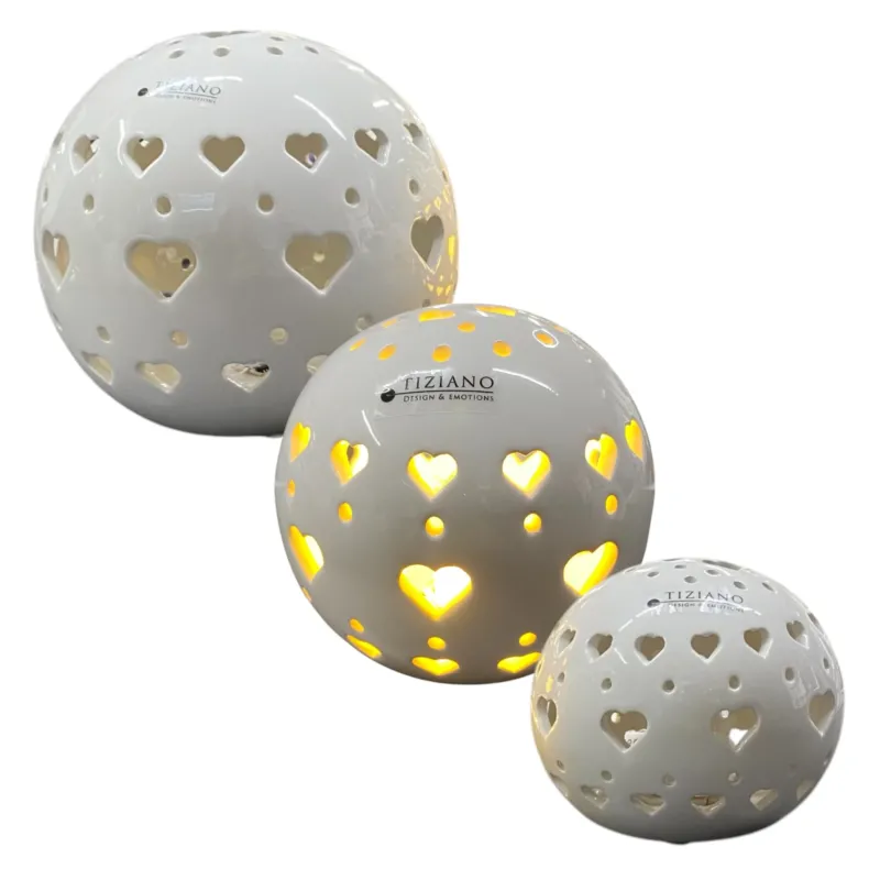 Drei Dekolicht Kugeln aus Keramik mit Herzen, aus denen warmes LED-Licht strahlt. Drei Größen sind vor weißem Hintergrund platziert.