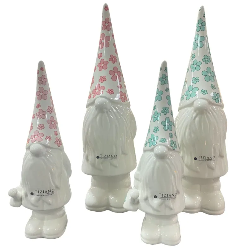 Weiße Keramik-Zwergfiguren mit langen Zipfelmützen, verziert mit rosa und mintfarbenem Blumenmuster, verschiedene Größen, freigestellt auf weißem Hintergrund
